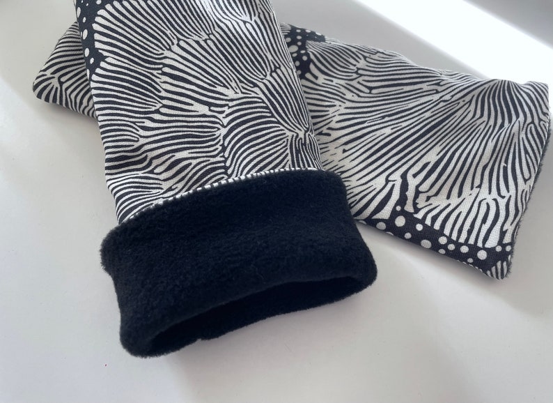 May include: Black and white patterned fingerless gloves with a black fleece lining.