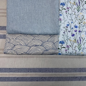 Puede incluir: Tres muestras de tela, una con un patrón de ondas azul y blanco, otra con un patrón floral azul y blanco y la última con un color azul sólido.