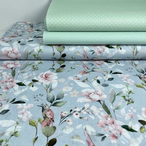 May include: A blue fabric with a floral pattern featuring pink roses, green leaves, and watercolour hummingbirds.