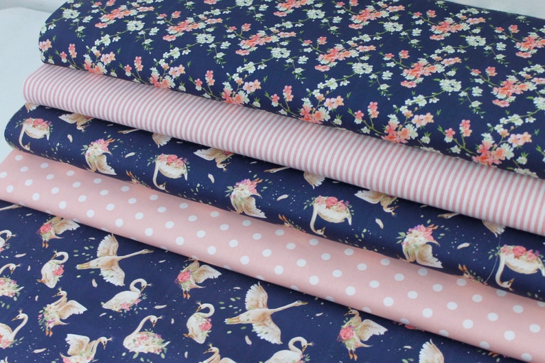 May include: Five fabric swatches in different patterns. The top swatch is a navy blue fabric with a white and pink floral print. The second swatch is a pink and white striped fabric. The third swatch is a navy blue fabric with a white polka dot pattern. The fourth swatch is a navy blue fabric with a white and pink floral print featuring swans. The bottom swatch is a navy blue fabric with a white and pink floral print featuring swans.