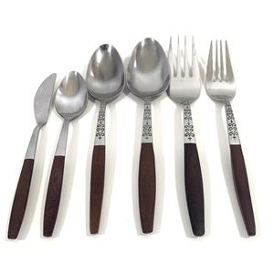 Può includere: Set di sei posate in acciaio inossidabile con manici in legno marrone. Il set comprende un coltello da burro, due cucchiai e due forchette.