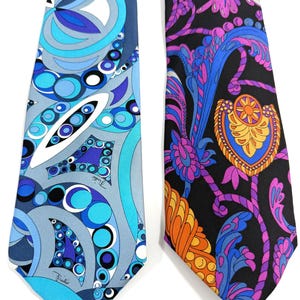 Puede incluir: Dos corbatas con patrones vibrantes. Una corbata presenta un diseño azul, blanco y gris con círculos y formas orgánicas. La otra corbata tiene un fondo negro con un diseño floral y paisley colorido en naranja, morado y azul.