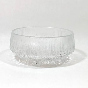 May include: A clear glass bowl with a textured, frosted finish. The bowl has a round shape and a wide, flat base.
