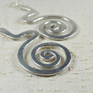 Puede incluir: Pendientes de plata con un dise&ntilde;o &uacute;nico en forma de espiral. Los pendientes est&aacute;n hechos de metal y tienen un aspecto simple y moderno.