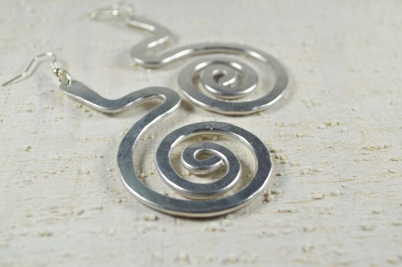 Puede incluir: Pendientes de plata con un dise&ntilde;o &uacute;nico en forma de espiral. Los pendientes est&aacute;n hechos de metal y tienen un aspecto simple y moderno.