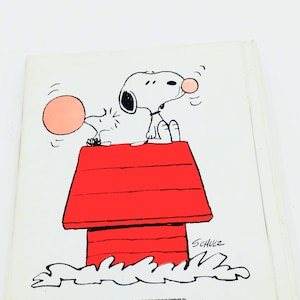 May include: A black and white illustration of Snoopy, the Peanuts character, sitting on top of his red doghouse. Snoopy is blowing a pink bubble and the bubble is about to pop. The image includes the text "SCHULZ" and "PEANUTS CHARACTERS: Copyright 1978 United Feature Syndicate, Inc."