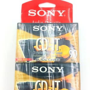 May include: Two packs of Sony CD-IT 90 minute audio cassette tapes. The cassette tapes are in a clear plastic slide case with a gold background. The packaging has the text "CD Performance and Sound" and "Slide Case" printed on it.