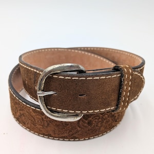 May include: A white ceramic mug with a black handle and the text "But First, Coffee" in a bold, black font. The mug is set against a neutral background, highlighting its simple design.