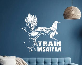 Puede incluir: Pegatina de pared de vinilo blanco con una imagen estilizada de un personaje de anime musculoso levantando pesas con el texto "TRAIN INSAIYAN".