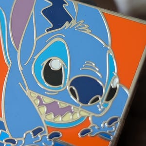 以下が含まれることがあります： リロ＆スティッチのキャラクター、スティッチが描かれた青いエナメルピン。青、紫、オレンジなど様々な色合いで詳細にデザインされています。アニメ映画のファンにぴったりのコレクターズアイテムです。