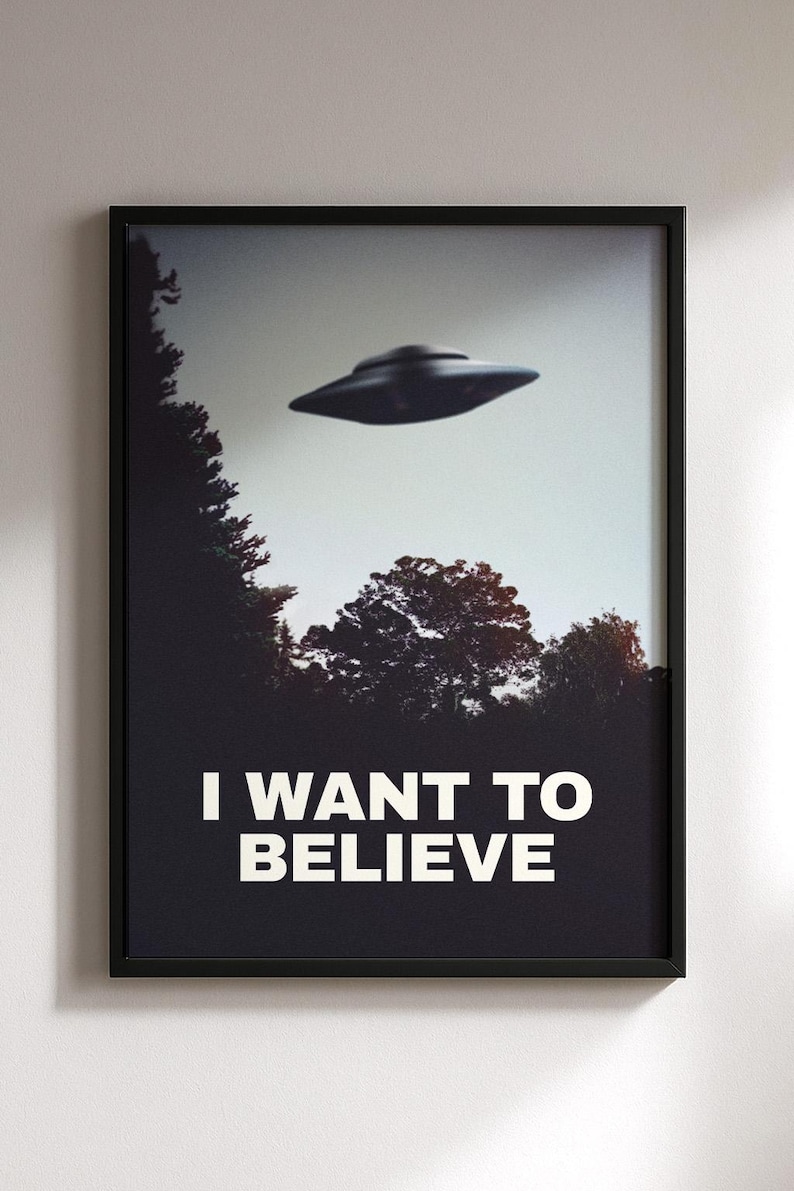 May include: A black framed poster with a black and white image of a flying saucer over a forest. The text "I WANT TO BELIEVE" is printed in white at the bottom of the poster.
