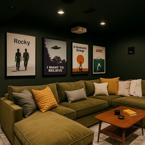 May include: A green sectional sofa with a chaise lounge, a coffee table, and several throw pillows. The wall behind the sofa is decorated with movie posters, including "Rocky", "I Want to Believe", "A Clockwork Orange", and "Jaws".