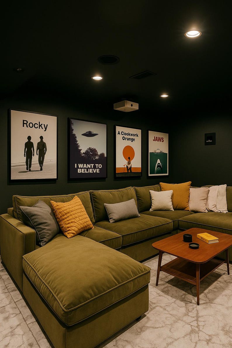 May include: A green sectional sofa with a chaise lounge, a coffee table, and several throw pillows. The wall behind the sofa is decorated with movie posters, including "Rocky", "I Want to Believe", "A Clockwork Orange", and "Jaws".