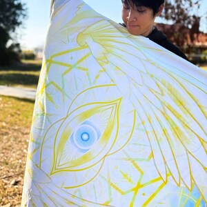 May include: A white and yellow blanket with a geometric and eye design. The blanket has a blue and yellow color scheme. The text "empath designs" is visible in the bottom corner.