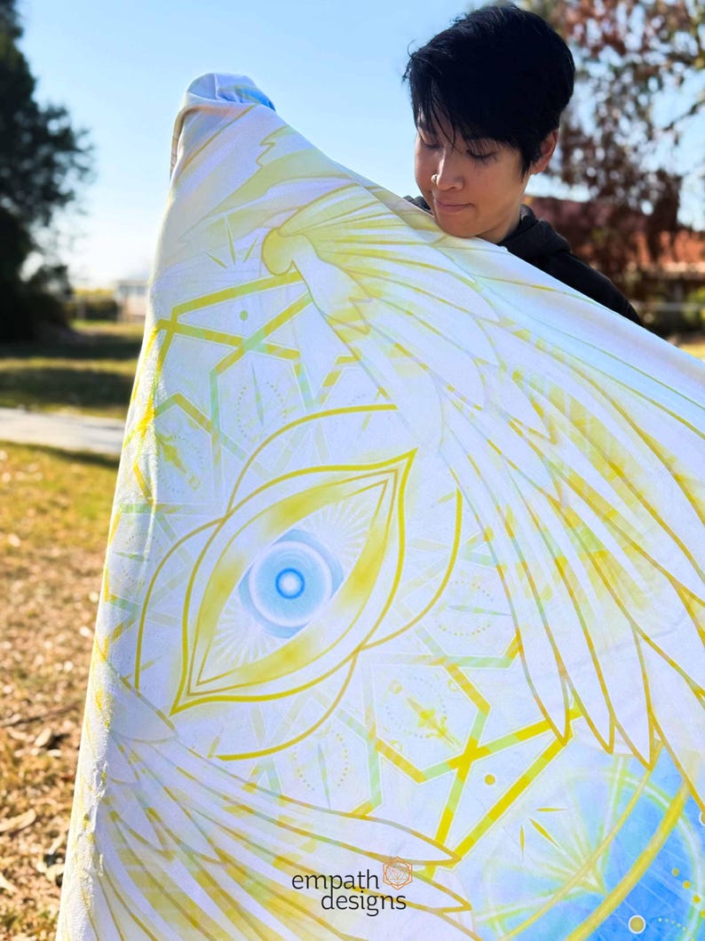 May include: A white and yellow blanket with a geometric and eye design. The blanket has a blue and yellow color scheme. The text "empath designs" is visible in the bottom corner.