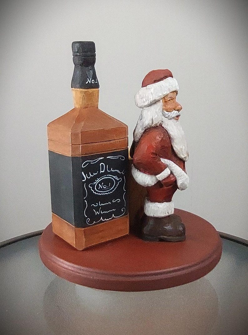 Puede incluir: Una figurita de madera de Pap&aacute; Noel sosteniendo una botella de whisky Jack Daniel's. La botella est&aacute; etiquetada con "Jack Daniel's No. 1 Tennessee Whiskey". La figurita est&aacute; de pie sobre una base redonda de madera.