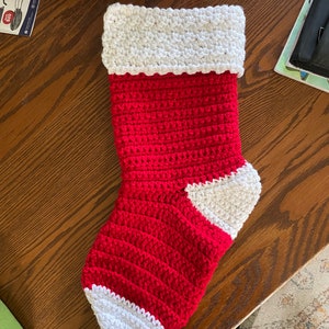 May include: A red and white crocheted Christmas stocking with a white cuff and toe.