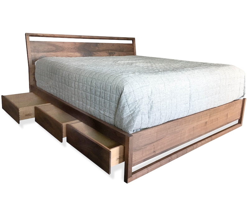 Puede incluir: Un marco de cama de madera con cabecera y piecero. El marco de la cama tiene tres cajones que est&aacute;n parcialmente abiertos. El marco de la cama est&aacute; hecho de madera oscura y tiene un dise&ntilde;o moderno.