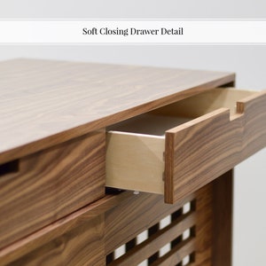 Puede incluir: Una c&oacute;moda de madera con dos cajones que tienen mecanismos de cierre suave. Los cajones est&aacute;n hechos de madera marr&oacute;n claro con un ribete de madera marr&oacute;n oscuro. La c&oacute;moda tiene un dise&ntilde;o de listones en la parte delantera.