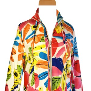 May include: A white jacket with a colorful floral print. The jacket has a zipper closure and long sleeves.