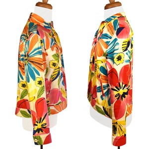 May include: A short-sleeved jacket with a colorful floral print. The jacket has a white background with large, bright flowers in shades of pink, orange, yellow, blue, and green.