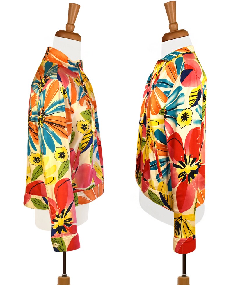 May include: A short-sleeved jacket with a colorful floral print. The jacket has a white background with large, bright flowers in shades of pink, orange, yellow, blue, and green.