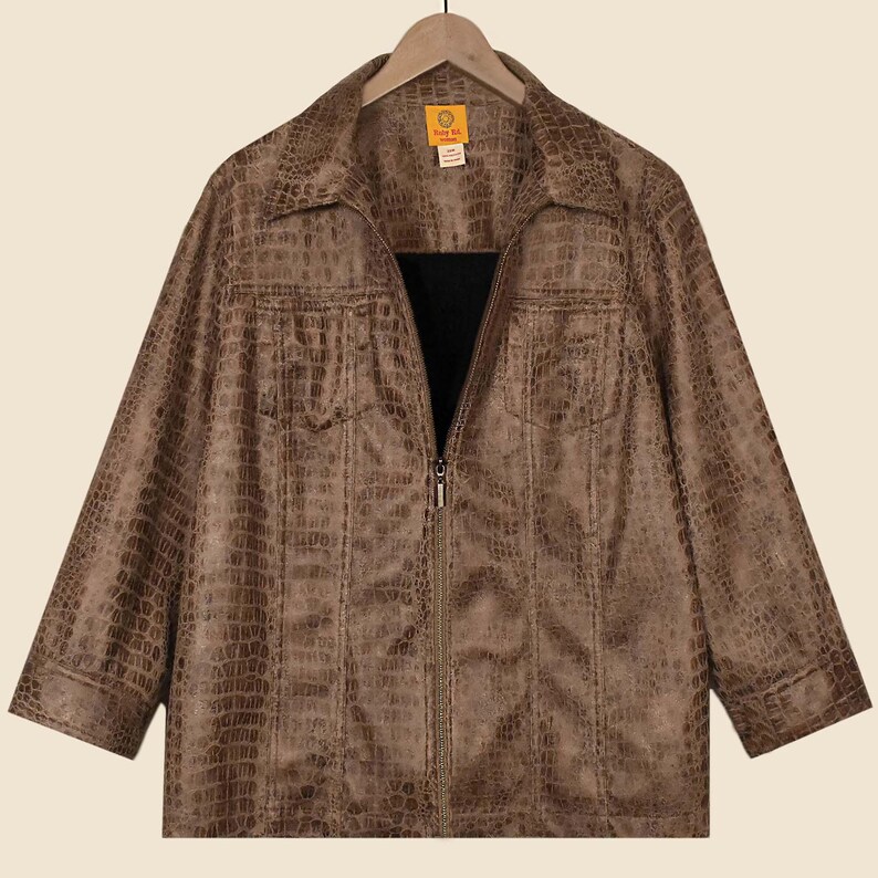 May include: Brown faux leather jacket with a crocodile skin texture. The jacket has a zip-up front, two chest pockets, and a collared neckline. The jacket is hanging on a wooden hanger.