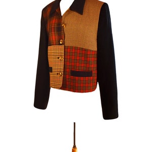 May include: A black, cropped jacket with a patchwork design. The jacket features four different plaid patterns in shades of red, brown, and yellow.