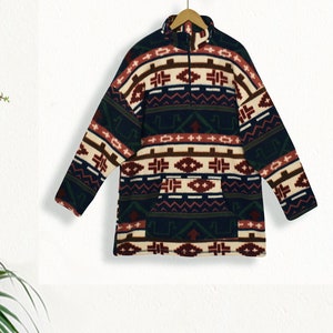 May include: A dark blue fleece pullover with a colorful geometric pattern in shades of red, brown, white, and green. The pullover has a mock neck and a zipper closure.