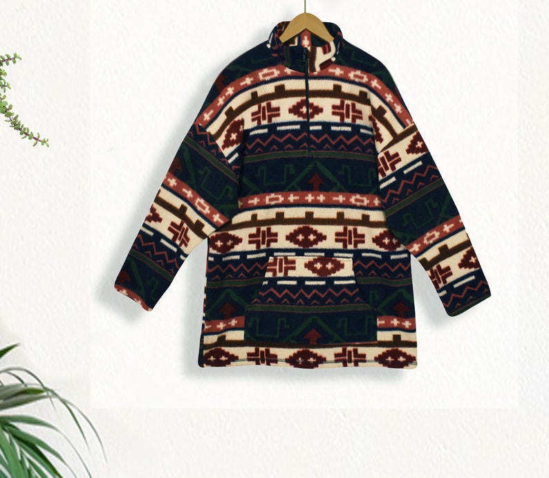 May include: A dark blue fleece pullover with a colorful geometric pattern in shades of red, brown, white, and green. The pullover has a mock neck and a zipper closure.