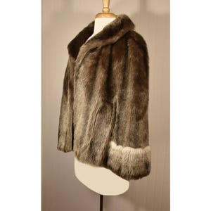 Peut inclure: Une veste en fausse fourrure marron avec un col et des poignets bord&eacute;s de fausse fourrure blanche. La veste est sur un mannequin blanc.