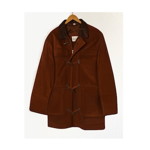 May include: A brown suede coat with a brown leather collar and toggle closures. The coat has two front pockets and a zipper closure.