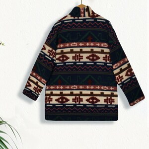 May include: A navy blue cardigan with a colorful geometric pattern. The pattern features red, white, brown, and green accents. The cardigan has a high neck and long sleeves.