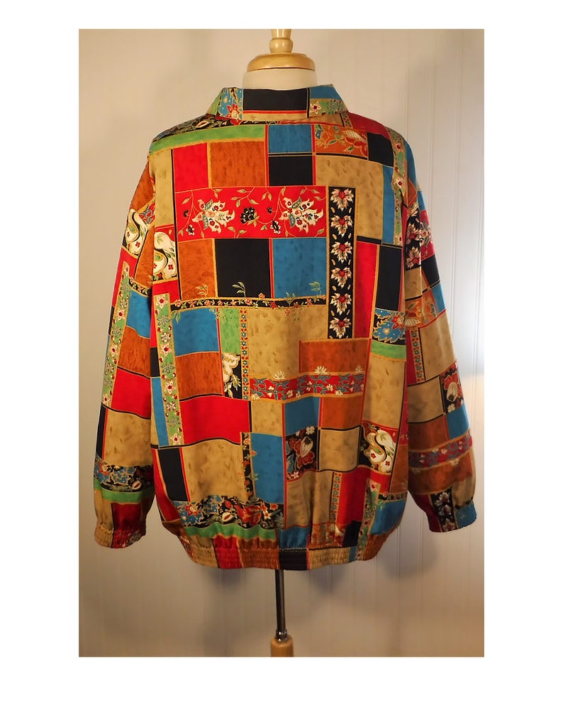 May include: A colorful, patterned jacket with a patchwork design featuring red, blue, green, black, and brown squares. The jacket has a zipper closure and a stand-up collar.