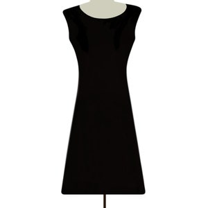 May include: A black sleeveless dress on a wooden dress form.
