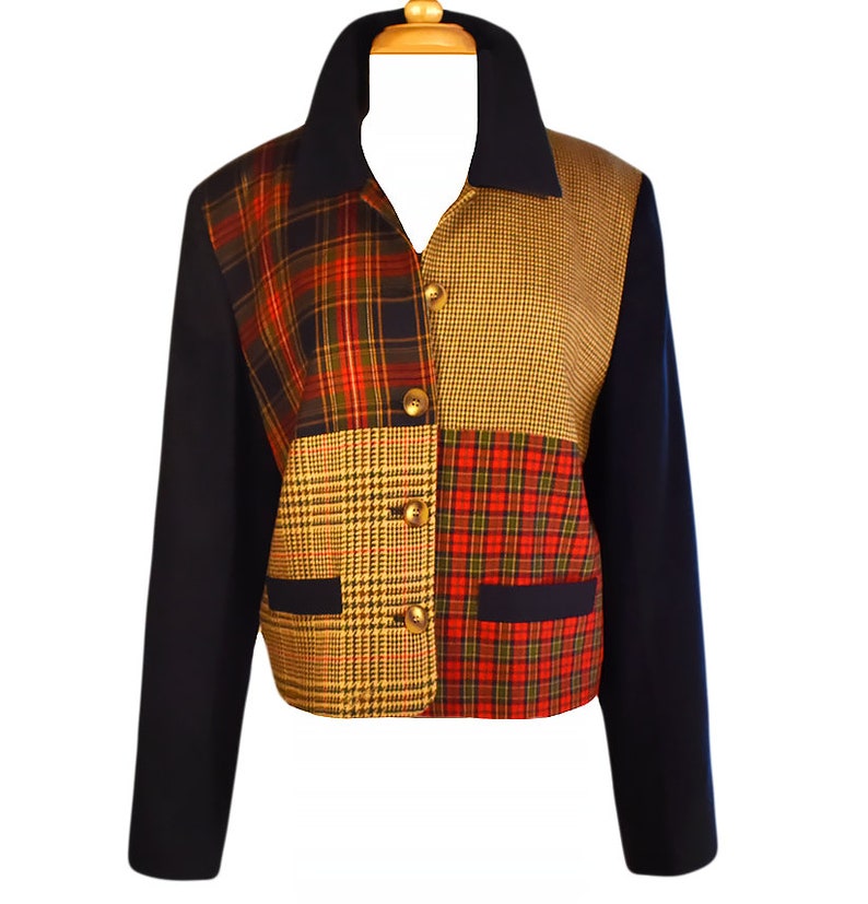 May include: A navy blue blazer with a patchwork design featuring red, green, and yellow plaid patterns. The blazer has a collar, long sleeves, and button closures.