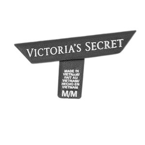 May include: A black and white clothing tag with the text "VICTORIA'S SECRET" in white lettering. The tag also includes the text "MADE IN VIETNAM" and "M/M".