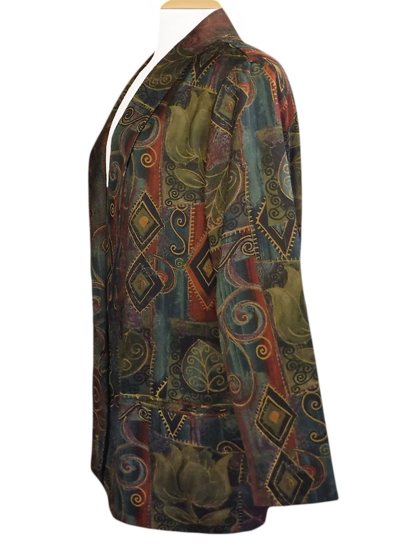 May include: A patterned blazer in shades of green, red, and brown, featuring geometric and floral designs. The jacket has a notched collar and two front pockets. The fabric appears to be a soft, possibly silk, material.