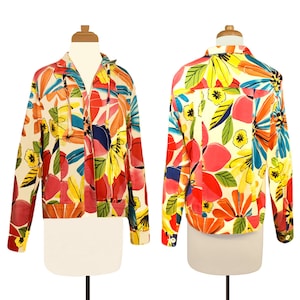 May include: A long-sleeved jacket with a zipper closure and a colorful floral print. The print features large, abstract flowers in shades of red, yellow, blue, green, and pink on a white background.