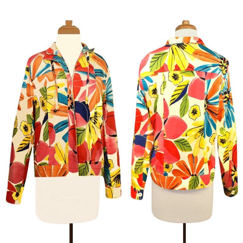 May include: A long-sleeved jacket with a zipper closure and a colorful floral print. The print features large, abstract flowers in shades of red, yellow, blue, green, and pink on a white background.