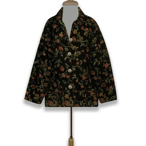 May include: A black jacket with a floral pattern in shades of green, orange, and yellow. The jacket has a button-up front and long sleeves.