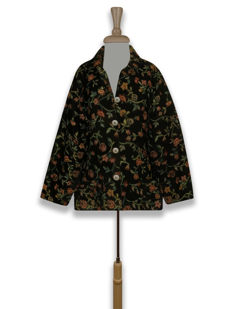 May include: A black jacket with a floral pattern in shades of green, orange, and yellow. The jacket has a button-up front and long sleeves.