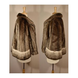 Peut inclure: Une veste en fausse fourrure marron avec une bordure blanche autour du bas et des manches. La veste est expos&eacute;e sur un mannequin.