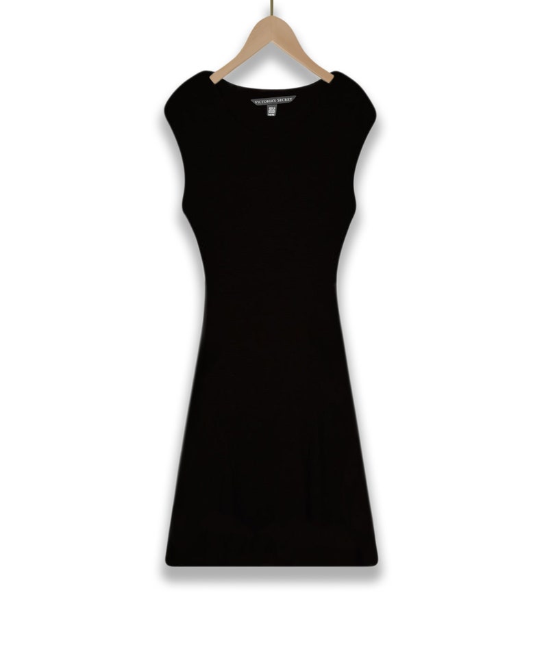 May include: A black sleeveless dress with a scoop neck and a fitted silhouette. The dress has a small tag that reads "Victoria's Secret".