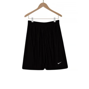 Puede incluir: Pantalones cortos deportivos negros con un logotipo blanco de Nike en forma de swoosh en la pierna derecha.