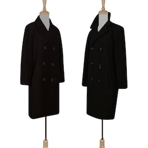 K&ouml;nnte beinhalten: Zwei schwarze Peacoats mit doppelreihigen Kn&ouml;pfen und Kragen. Die M&auml;ntel befinden sich auf Mannequins mit Holzsockeln.