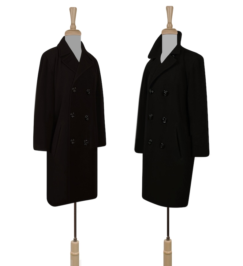 K&ouml;nnte beinhalten: Zwei schwarze Peacoats mit doppelreihigen Kn&ouml;pfen und Kragen. Die M&auml;ntel befinden sich auf Mannequins mit Holzsockeln.