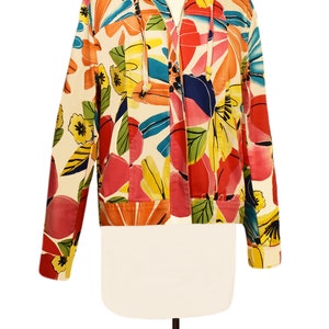 May include: A white jacket with a colorful floral print. The jacket has a zipper closure and a hood.