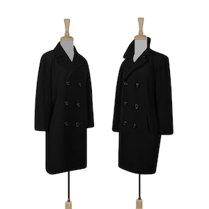 K&ouml;nnte beinhalten: Zwei schwarze Peacoats mit doppelreihigem Verschluss und schwarzen Kn&ouml;pfen. Die M&auml;ntel befinden sich auf Mannequins mit Holzst&auml;ndern.