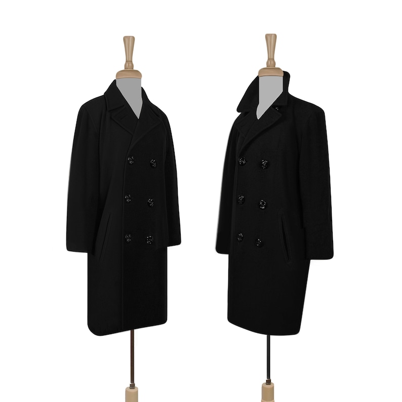 K&ouml;nnte beinhalten: Zwei schwarze Peacoats mit doppelreihigem Verschluss und schwarzen Kn&ouml;pfen. Die M&auml;ntel befinden sich auf Mannequins mit Holzst&auml;ndern.